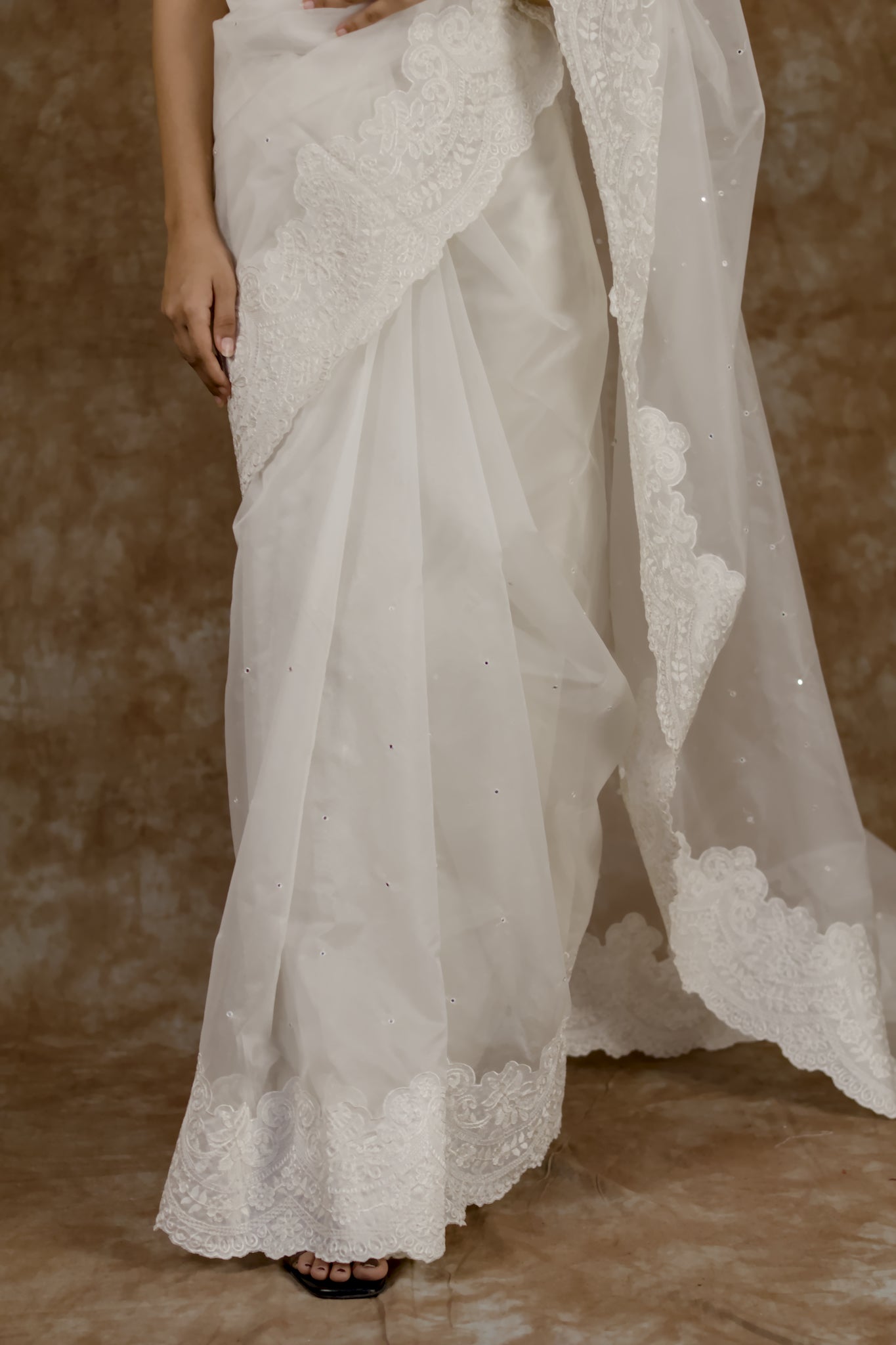 White lace saree with a brown background